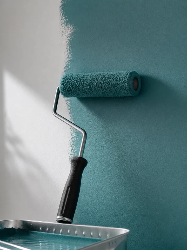 Paint roller applying a teal finish